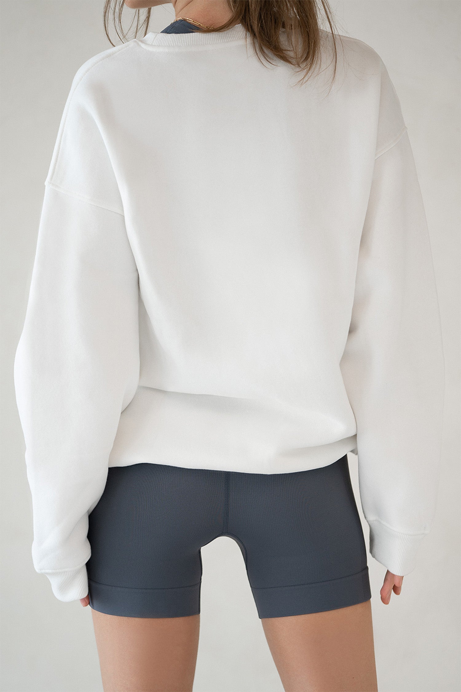 Model in Aurelia Raw Layover Pullover from behind with hands relaxed and fleece texture visible