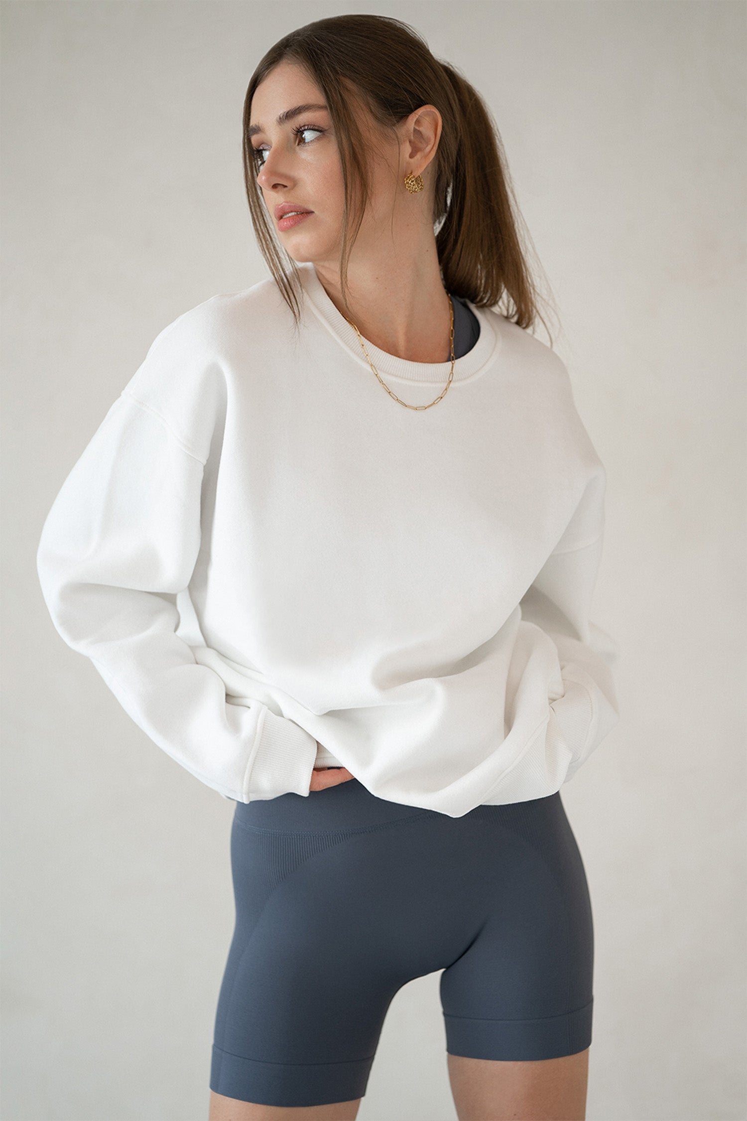Side view of Aurelia Raw Layover Pullover with relaxed fit and gold jewelry accent