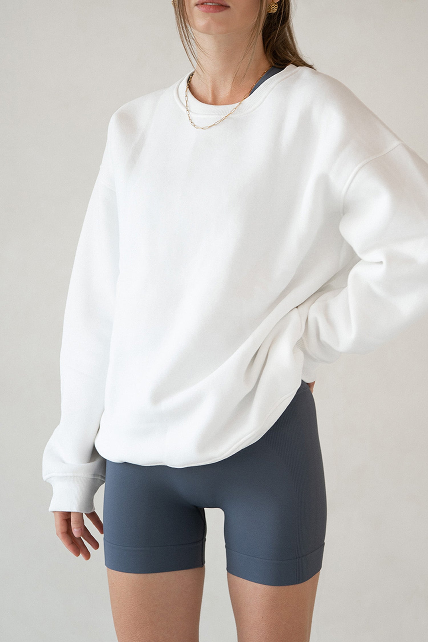 Close shot of model wearing Aurelia Raw Layover Pullover from front and grey yoga shorts