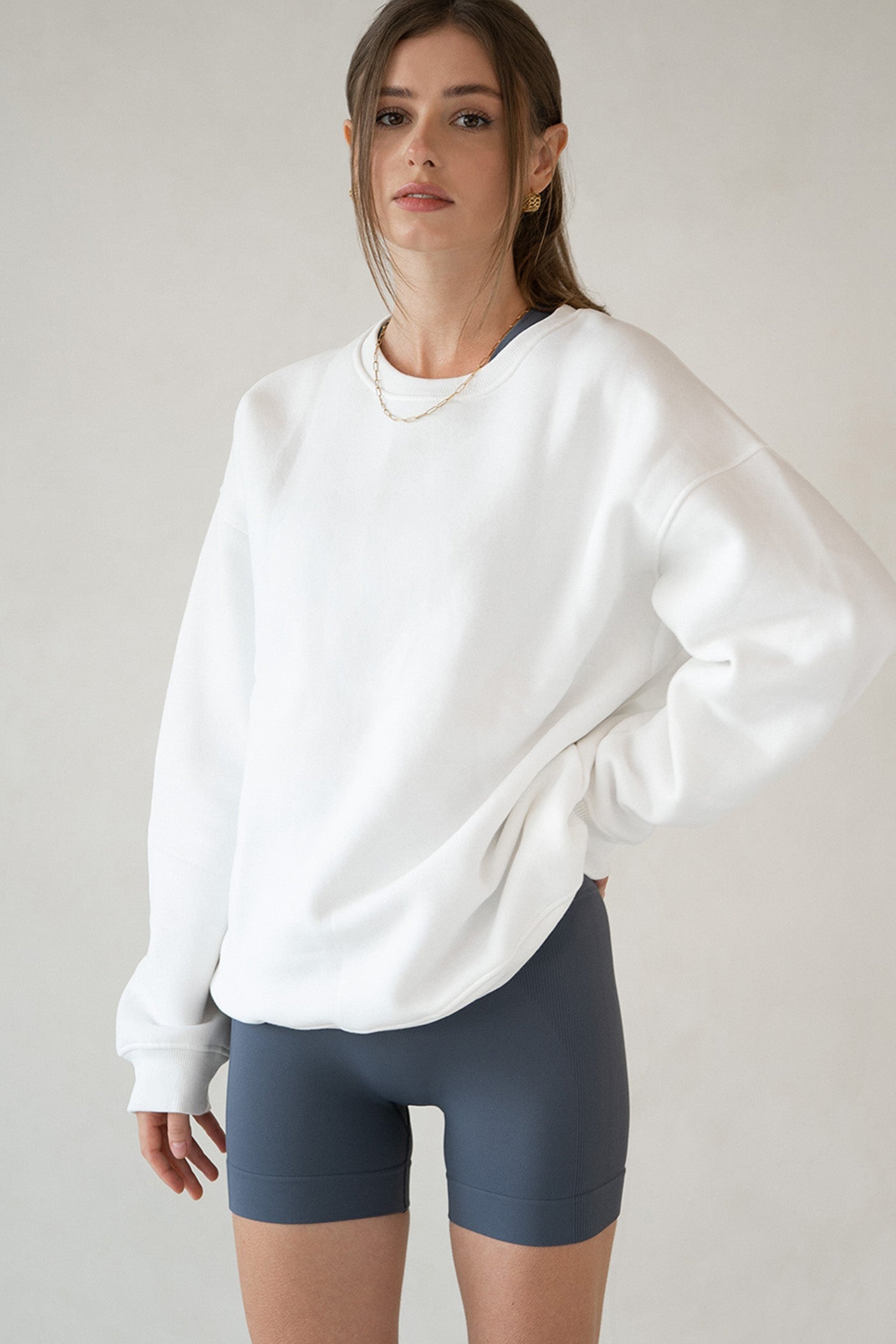 Model wearing Aurelia Raw Layover Pullover from front with oversized white crewneck and grey yoga shorts