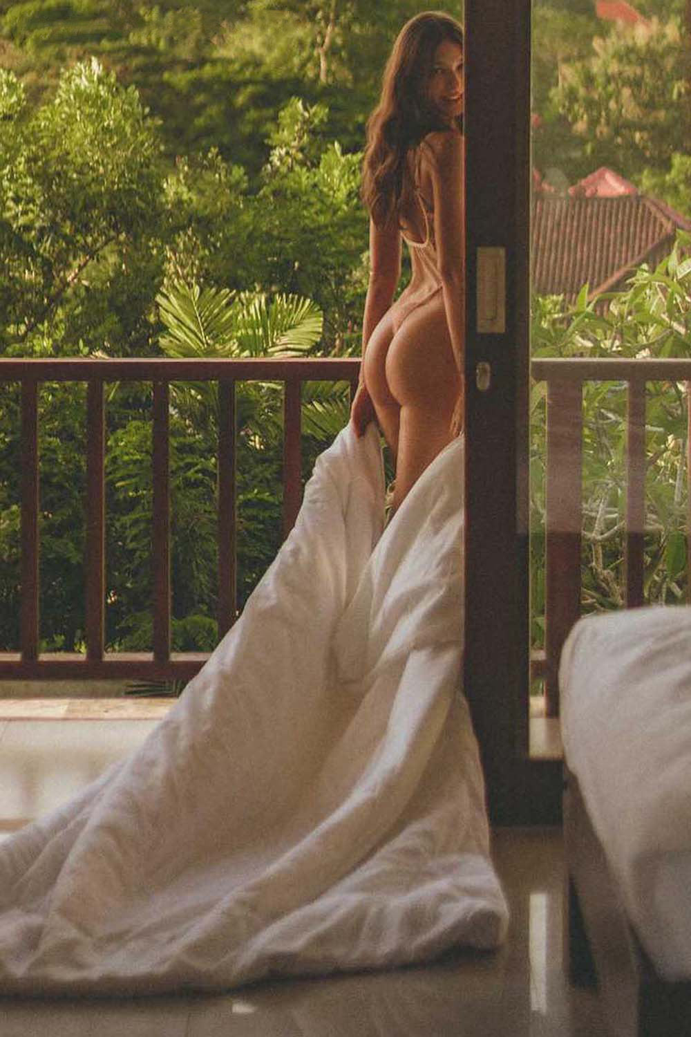 Woman standing on balcony in Aurelia Raw Violante One-Piece with tropical background